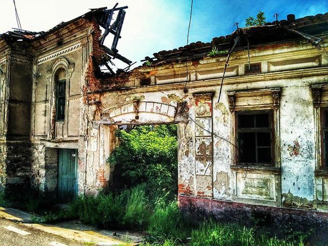 architecture, built structure, building exterior, abandoned, old, damaged, obsolete, house, run-down, deterioration, weathered, bad condition, sky, residential structure, ruined, window, grass, destruction, low angle view, old ruin