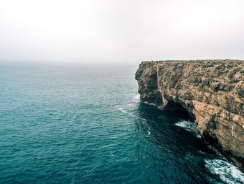 Rock formation in sea against clear sky