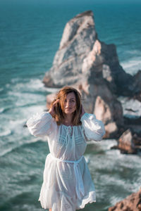 Woman standing on rock by sea