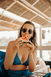 Portrait of a young woman sitting and eating watermelon