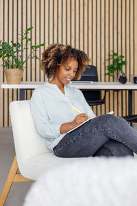 Young woman using laptop while sitting on sofa at home