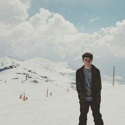 Portrait of smiling young man standing on snowcapped mountain