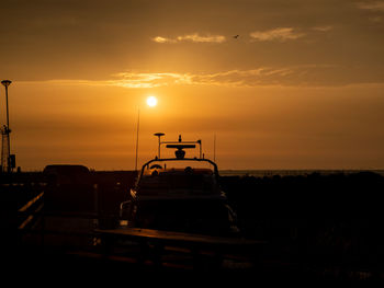 Silhouette cars on road against sky during sunset