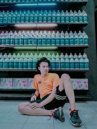 Full length portrait of woman sitting in shelf