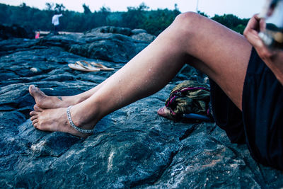 Low section of woman relaxing on rock