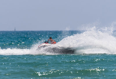 Man on jet boat on sea against clear sky during sunny day