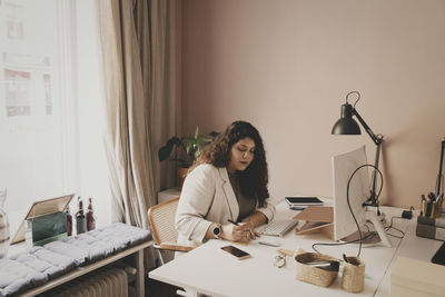 Young businesswoman working while sitting at desk in office