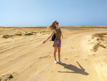 Full length of woman on beach against clear sky