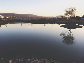 Scenic view of lake against clear sky at sunset