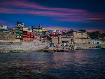 Buildings at waterfront against cloudy sky