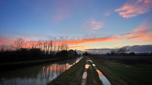 Scenic view of canal against sky during sunset