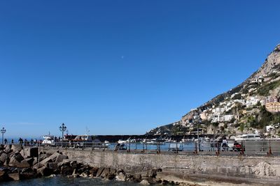 People on beach against clear blue sky