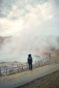 Rear view of man standing on mountain against sky