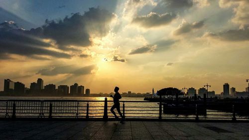 Silhouette of people on railing at sunset