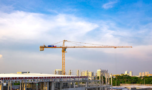 Cranes at construction site against sky in city