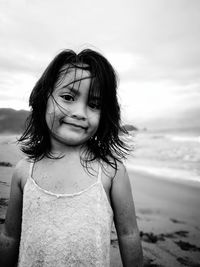 Portrait of girl standing at beach against sky