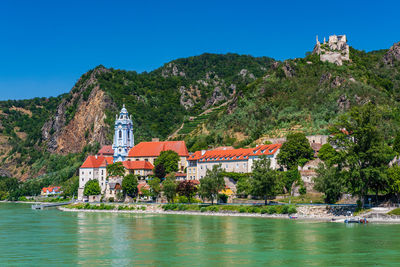 Buildings at waterfront against blue sky