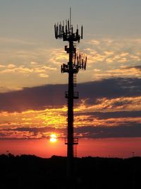 Low angle view of silhouette communications tower against sky during sunset