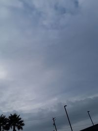 Low angle view of communications tower against cloudy sky