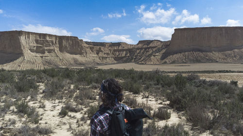 Rear view of man standing on mountain against sky