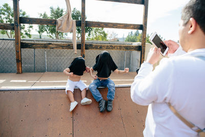 Father takes a picture of his children with shirts over their heads