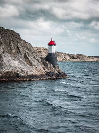 Lighthouse by sea against sky