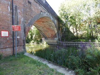 Arch bridge over canal against trees