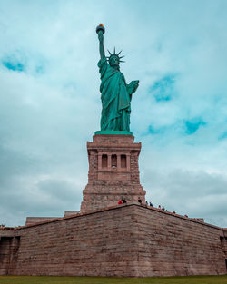 Low angle view of statue of liberty against cloudy sky