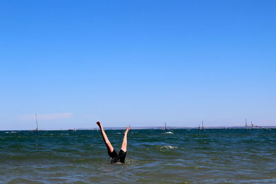 Man in sea against clear blue sky