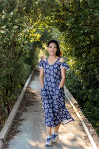 Portrait of young woman standing against trees