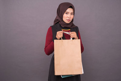 Portrait of young woman standing against white background