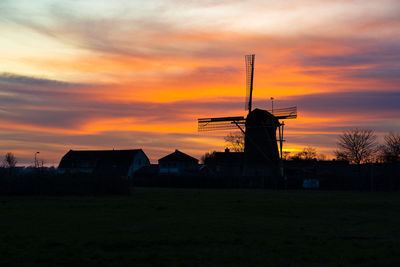 Silhouette built structure on land against sky during sunset