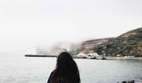 Rear view of woman by sea against sky