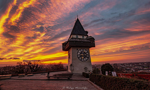 Clock tower amidst buildings against sky during sunset