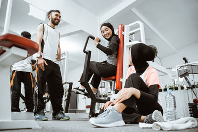 Portrait of smiling friends using digital tablet while standing in gym
