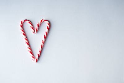 Candy canes arranged in a heart shape on a plain white background.