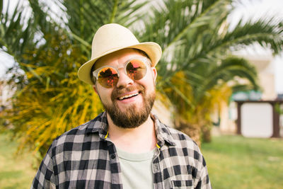 Portrait of young man wearing sunglasses against trees