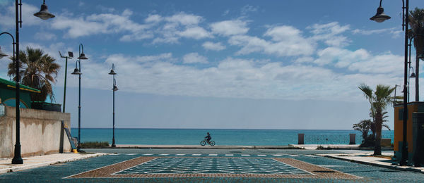 Street by sea against sky during sunny day