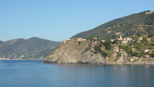 Scenic view of sea and buildings against clear blue sky