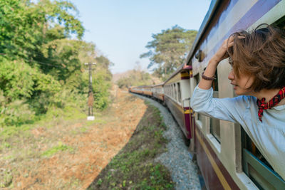 Portrait of woman on train amidst trees