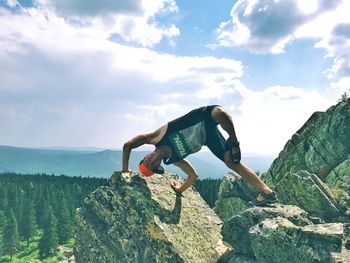 Man standing on rock against sky