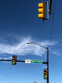 Low angle view of road sign against blue sky