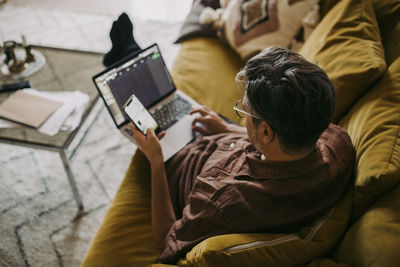 High angle view of male entrepreneur working on laptop in living room