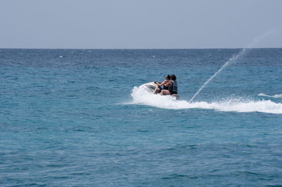 Man and woman riding jet boat in sea