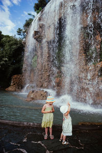 People standing against waterfall