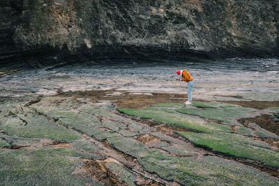 Side view of woman standing against rock formation