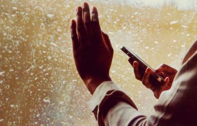 Close-up of man holding mobile phone in water