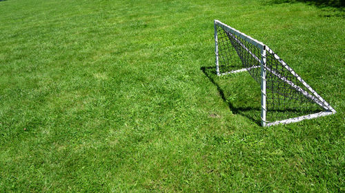 View of freestanding mini soccer goal post net on outdoor football green grass field copy space