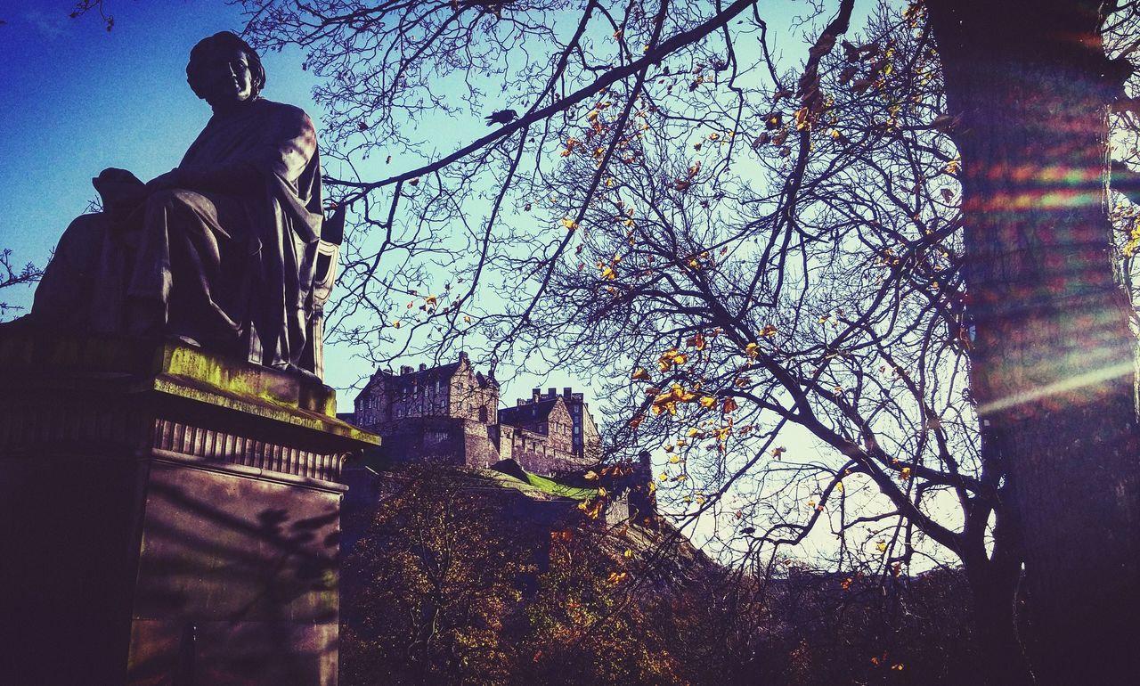 low angle view, architecture, built structure, building exterior, statue, human representation, art and craft, sculpture, art, creativity, tree, sky, religion, spirituality, bare tree, branch, church, window