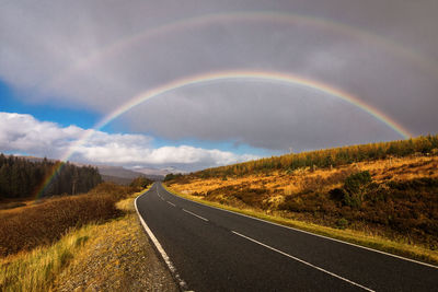 Scenic view of rainbow over road against sky